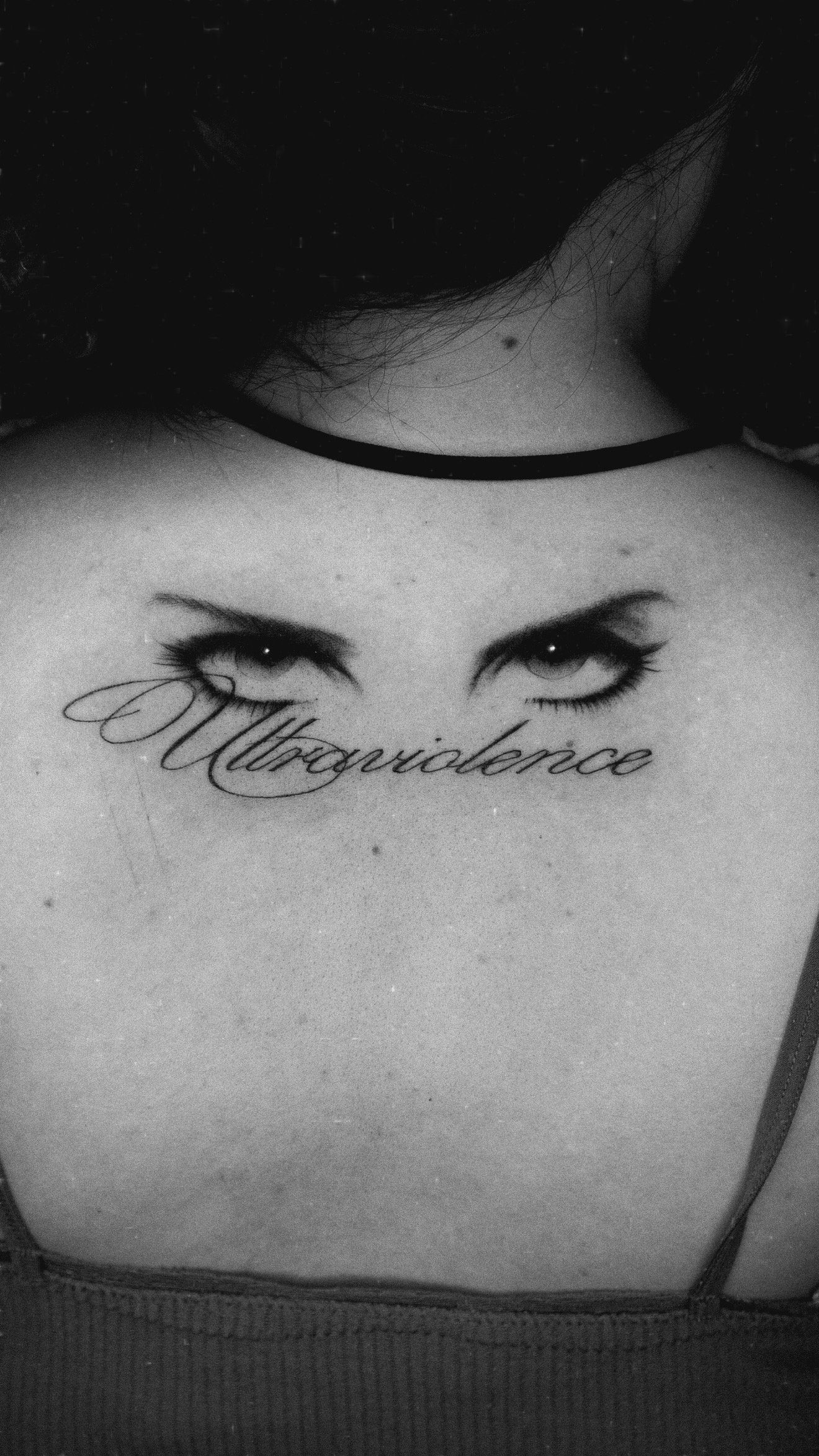 Upper-chest tattoo of two eyes above the script Ultraviolence.